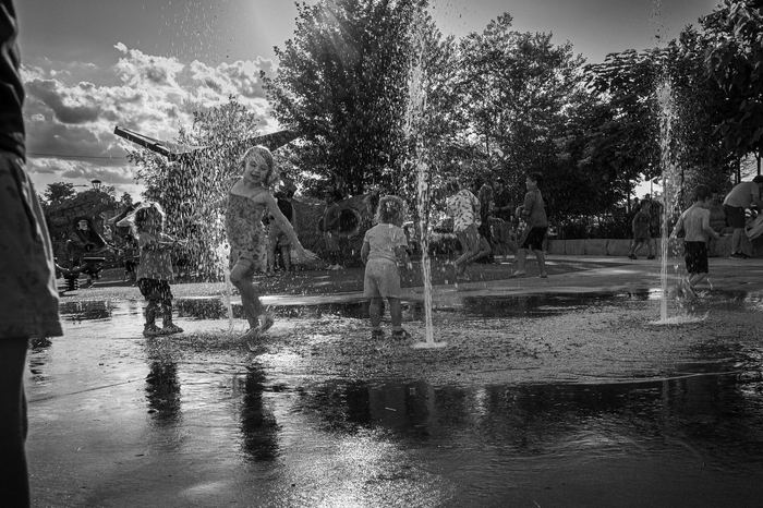 Kids cool off at the splash pad while the music carries across the park.